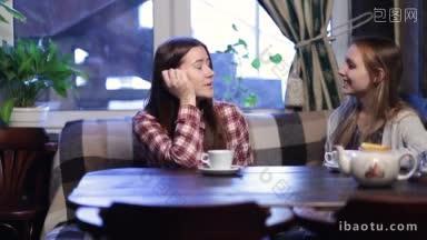 两个年轻漂亮的女朋友坐在现代化的咖啡馆里，一边聊着开心的微笑，一边等着她们的朋友<strong>可爱</strong>